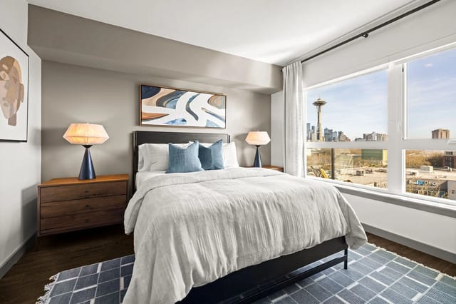 Bedroom with a king-size bed, nightstands, and a city view.