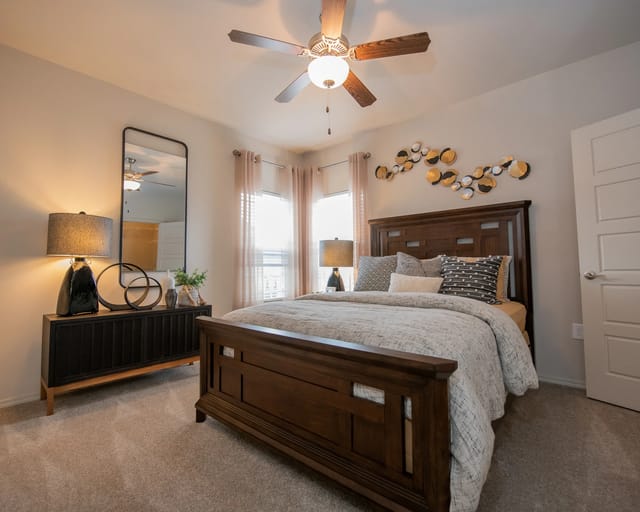 A bedroom with a large bed, a ceiling fan, and a mirror.