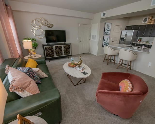 A living room with a green couch, a red chair, and a coffee table.