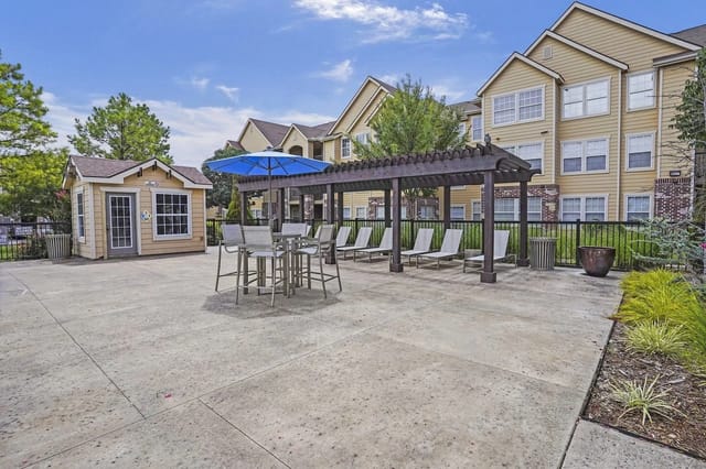 Patio area with tables, chairs, lounge chairs, and a pergola.