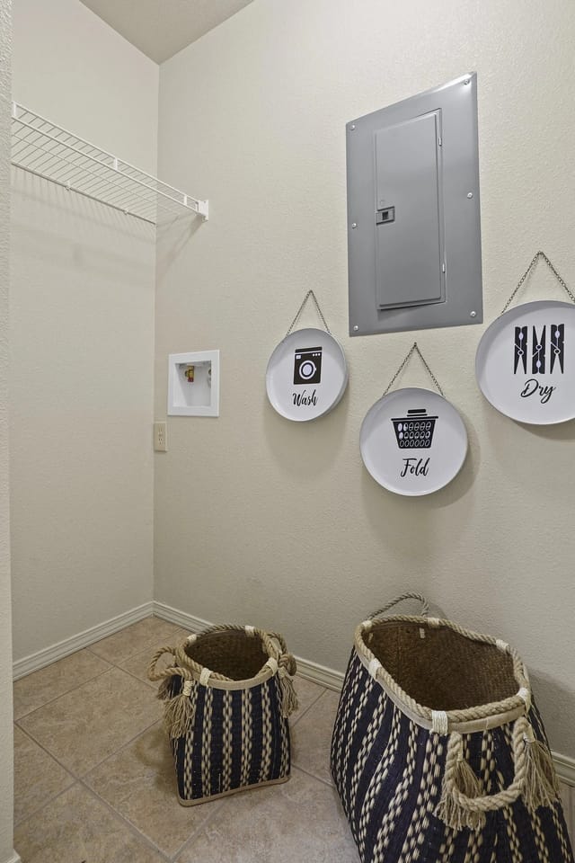 Laundry room with washer/dryer hookups, shelf, and decorative baskets.