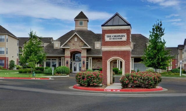 Exterior view of The Colonies at Hillside community entrance with a landscaped roundabout and brick sign.