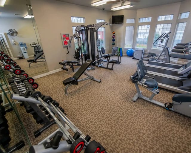 Interior of a community gym with treadmills, weights, and benches.