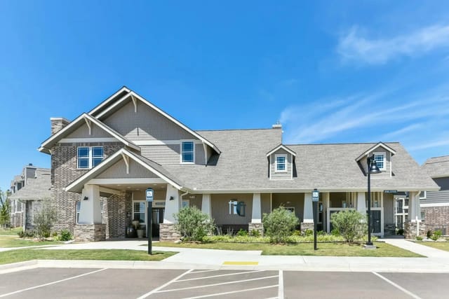 Exterior view of a modern apartment community building with a covered entrance and signage.