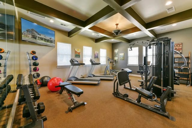 On-site apartment community gym with treadmills, free weights, a weight rack, and a multi-station machine.