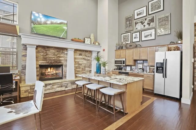 Open-concept living area with a stone fireplace, marble island, and stainless-steel appliances.