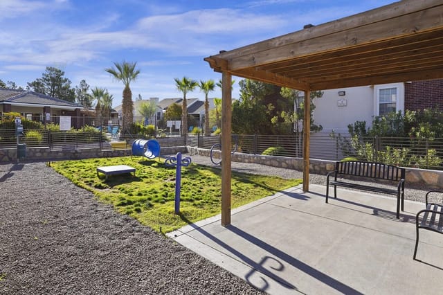 Outdoor community courtyard with a wooden pergola, benches, and a small play area.