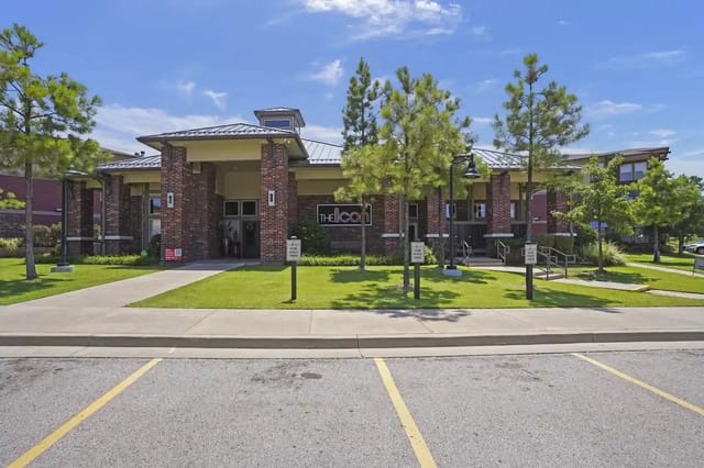 Exterior view of a brick apartment community building with a manicured lawn and the "The Icon" sign.