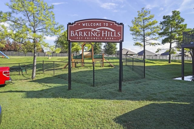 Exterior view of Barking Hills sign with a fenced grassy playground behind.