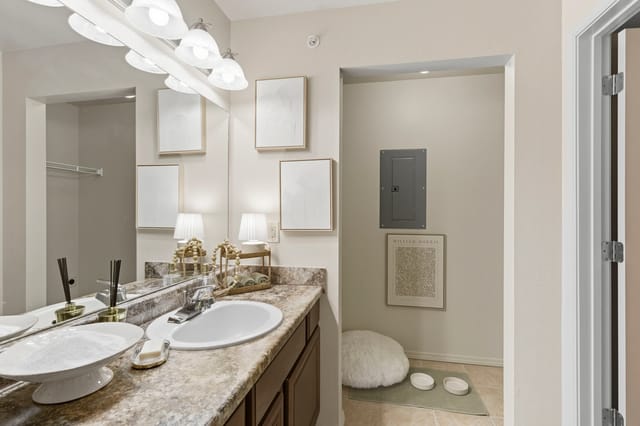 A bathroom vanity with a sink, marble countertops, and a large mirror.