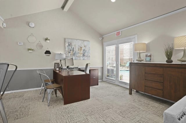 Leasing office area with a wooden desk, chairs, and glass doors.