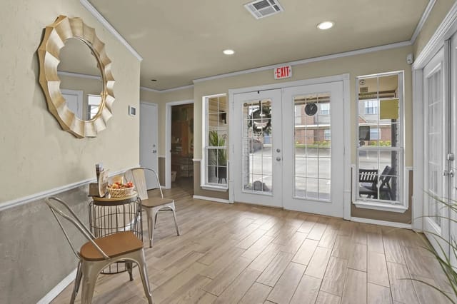Interior building lobby with glass doors, exit sign, and seating.