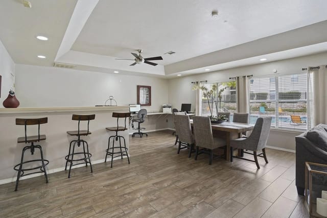Communal dining area with a table and chairs, bar seating, and a view of the pool.