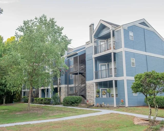 Exterior view of a blue multi-unit apartment building with balconies and landscaping.