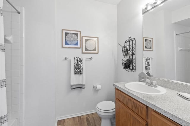 Bathroom with sink, mirror, toilet, and shower in an apartment unit.