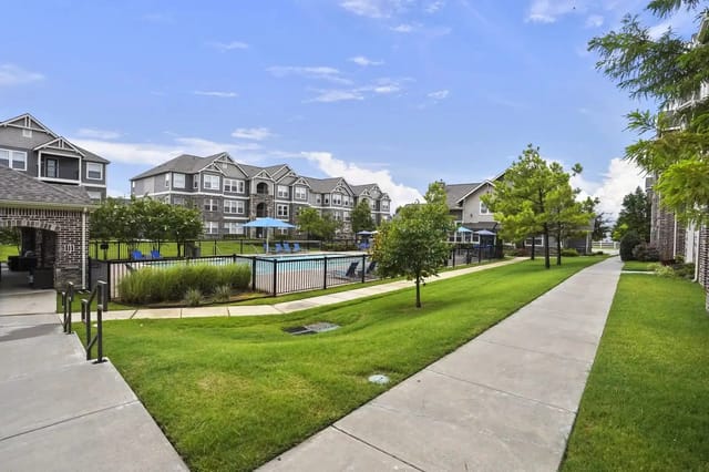 Exterior view of a residential apartment community with a central pool and manicured grounds.