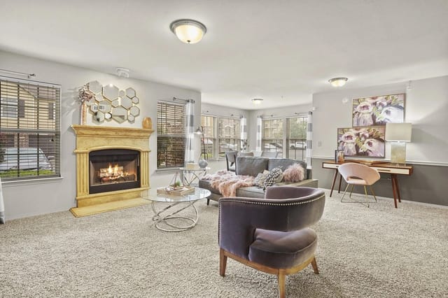 Spacious resident lounge with a gas fireplace, comfortable seating, and large windows.