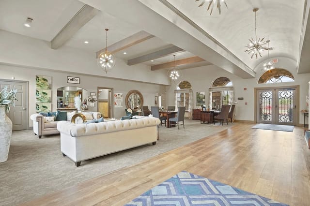 Spacious apartment lobby with couches, coffee station, and arched windows.