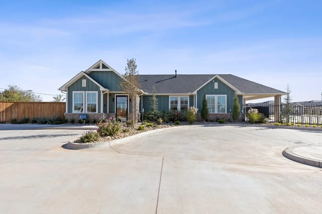 Exterior view of a modern apartment community building with a curved driveway and landscaped entrance.