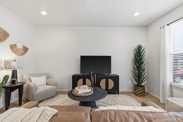 Modern living room with a leather couch, accent chair, coffee table, and TV.