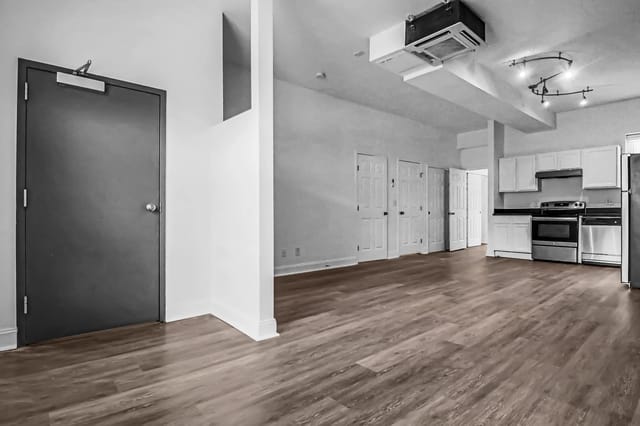 Interior view of a kitchen and living area with hardwood floors and white cabinets.