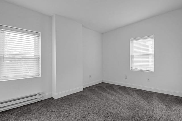 Empty bedroom with two windows and blinds.