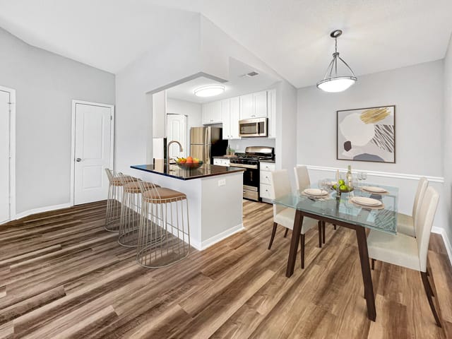 Modern kitchen and dining area with breakfast bar and glass-top dining table.