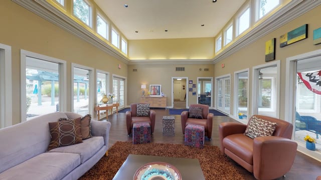 Interior lounge area with comfortable seating and large windows overlooking an outdoor pool.
