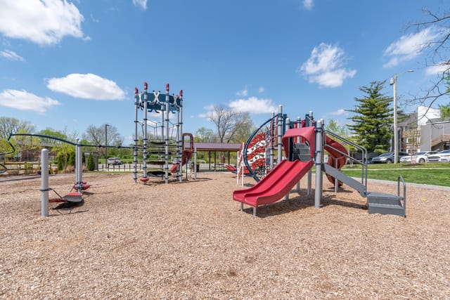Playground with climbing structures and slides on wood chip ground.