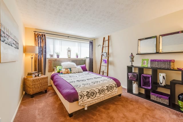 Bedroom with a queen-sized bed, nightstand, and shelving unit.