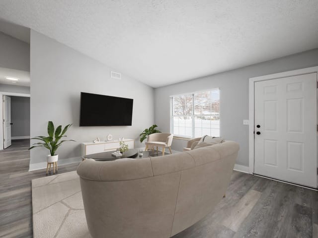 Living room with a sofa, armchair, coffee table, and TV mounted on the wall.