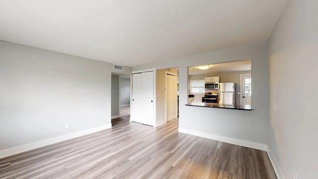 Empty living room with a view into the kitchen.