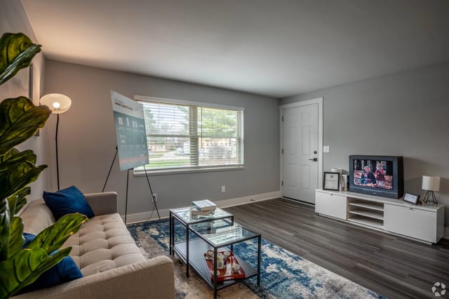 Living room with a sofa, coffee table, TV, and a presentation board.
