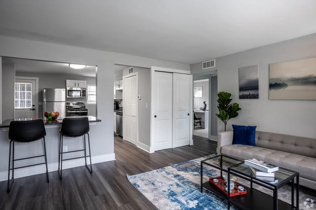 Living room with modern sofa and coffee table adjacent to a breakfast bar and kitchen.