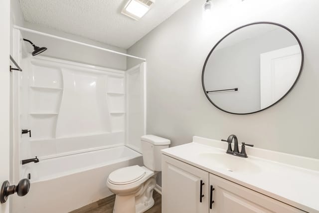 Modern bathroom with white vanity, round mirror, and white bathtub with shower.