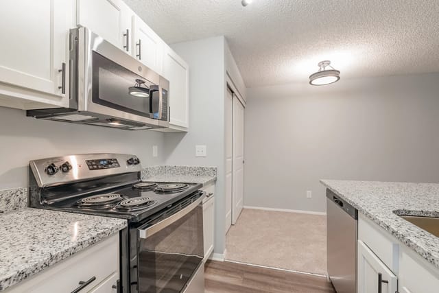 Kitchen with stainless steel appliances, granite countertops, and white cabinets.