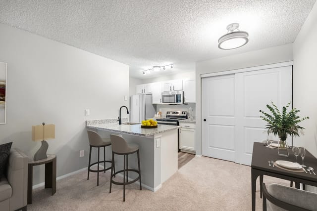Modern kitchen with granite countertops, stainless steel appliances, and breakfast bar with stools.