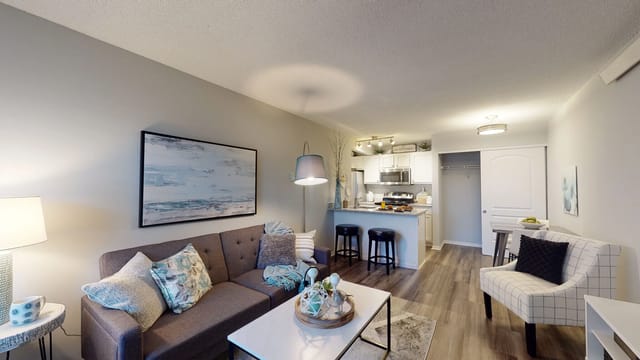 Modern living room and kitchen area with a sofa, coffee table, and breakfast bar.