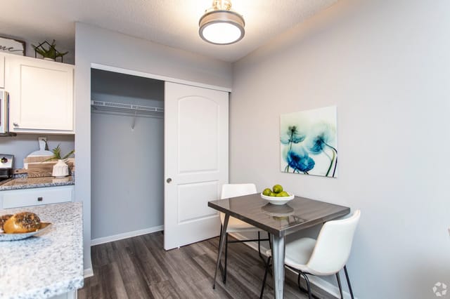 Dining area with a small table and chairs next to a closet.