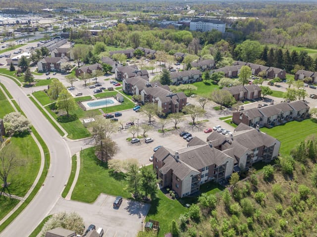Aerial view of apartment buildings, parking lots, and an outdoor swimming pool.
