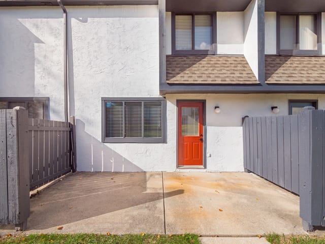 Exterior view of a townhome with a red front door and a private patio.
