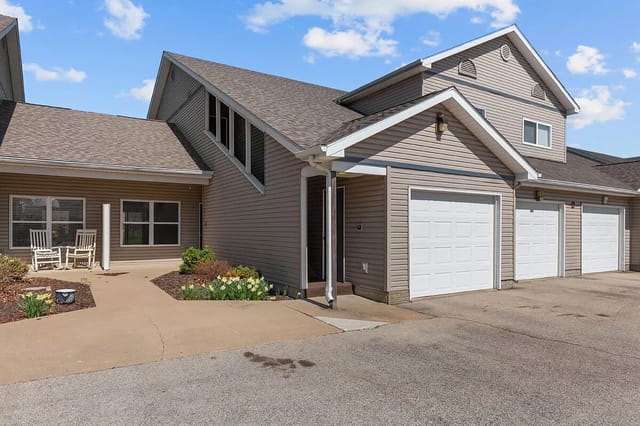 Exterior of apartment buildings with garages and a small seating area on the patio.