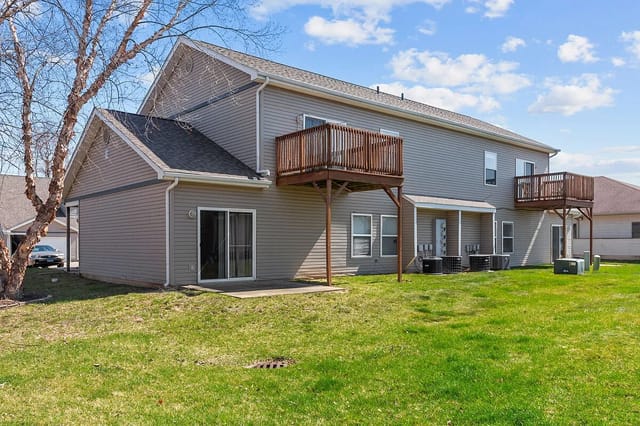 Rear exterior of a multifamily property with two levels, siding, and balconies.