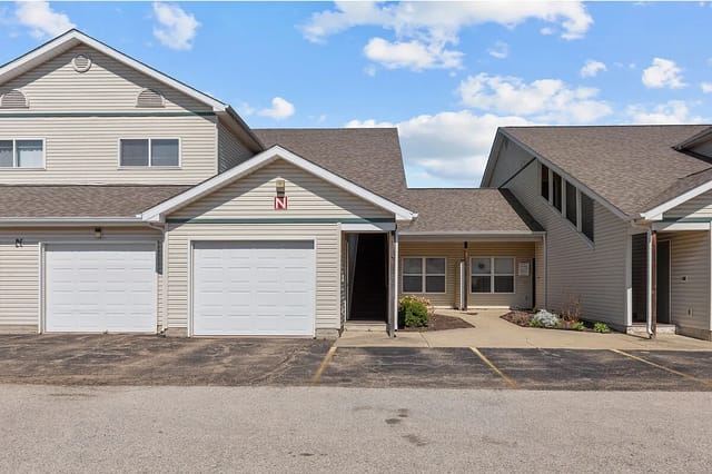 Exterior view of apartment building with attached garages and parking lot.