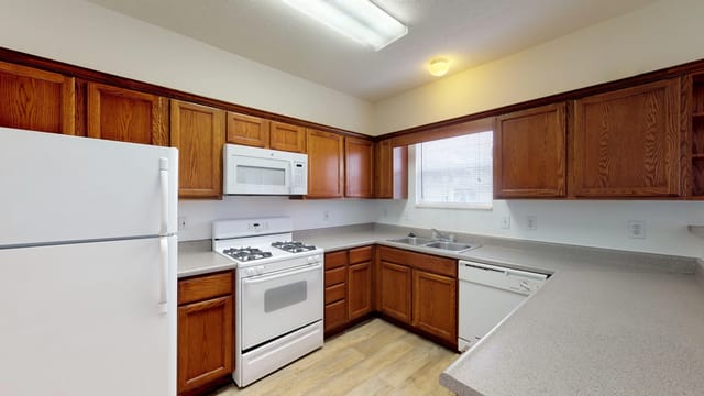 Kitchen with wood cabinets, white appliances, and a gas stove.