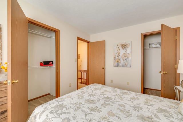 Bedroom with white comforter on bed and two closets.