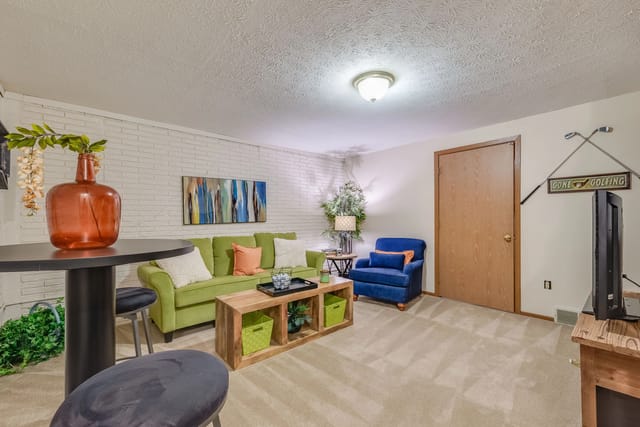 Cozy living room with green sofa, blue armchair, coffee table, and decor.