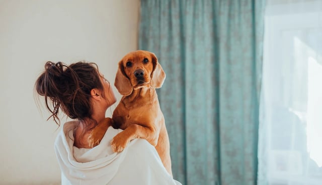 Woman holding a dog indoors.