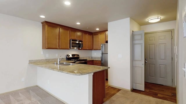 Kitchen area with granite countertops, stainless steel appliances, and wood cabinets.