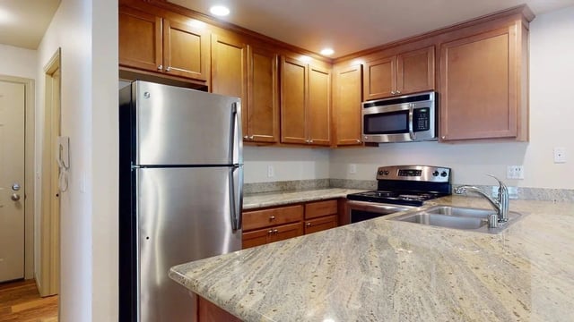 Kitchen with stainless steel refrigerator, microwave, stove, and granite countertops.